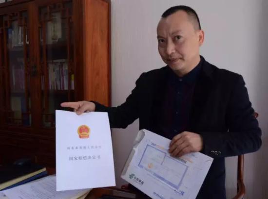状师辜光伟向记者展现国度抵偿认定书