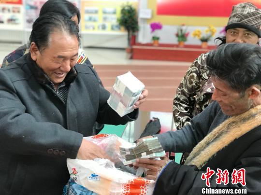 图为牧平易近将分成现金装进麻袋。　孙睿 摄
